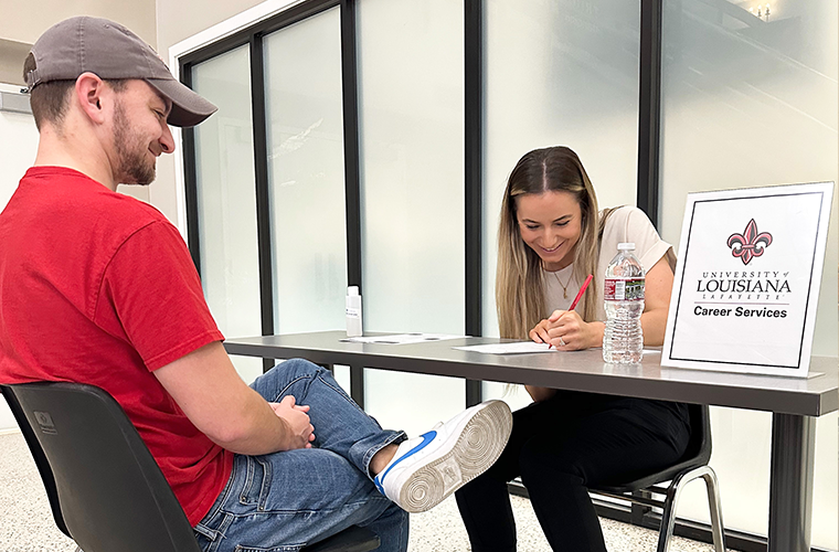 A Career Services representative helps a graduating student with his resume 